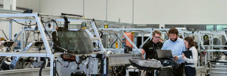 Defense contractors reviewing CMMC Title 48 compliance requirements in manufacturing facility